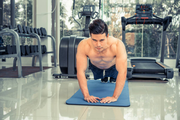 Young man bodybuilder doing push up in fitness center. Healthy lifestyle and body building concept.