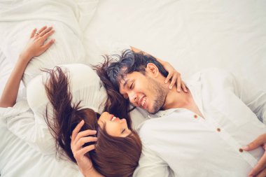Mutlu genç çift rahatlatıcı sabah uyandıktan sonra eve yatak odasında.