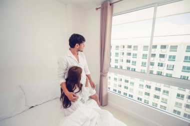 Mutlu genç çift rahatlatıcı sabah uyandıktan sonra eve yatak odasında.