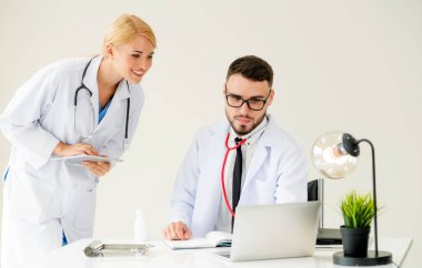 Doktor hastane ofis dizüstü bilgisayar masanın üzerinde başka bir doktor hasta sağlık hakkında tartışma ile çalışma.