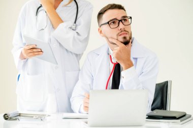 Doktor hastane ofis dizüstü bilgisayar masanın üzerinde başka bir doktor hasta sağlık hakkında tartışma ile çalışma.