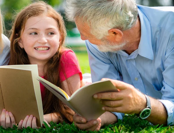 幸福的家庭一起读书 躺在公共公园的绿草上 在户外花园里和父亲一起学习的小女孩 教育和家庭生活方式 — 图库照片