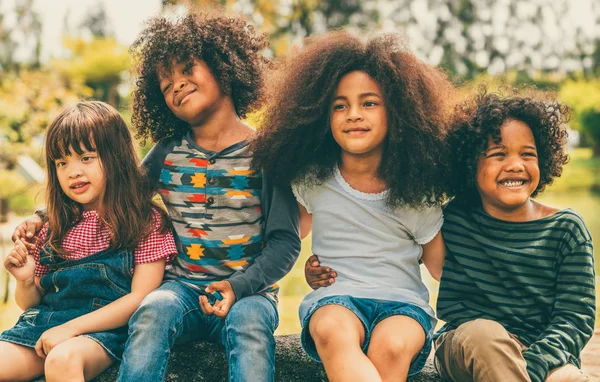 Foto Namoradinhas negras sentadas em banco de madeira e brincando ao ar  livre. Conceito de infância. Ideia de amizade. Estilo de vida infantil  moderno. Meninas morenas cacheadas alegres. Ensolarado durante o dia –