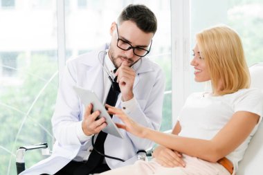 Erkek doktor ve Bayan hasta sağlık veri kaydı için tablet bilgisayar bakıyor. Sağlık ve tıbbi hizmet.
