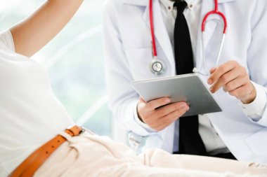 Erkek doktor konuşuyor ve Bayan hasta hastane ofisinde inceleyerek. Sağlık ve tıbbi hizmet.