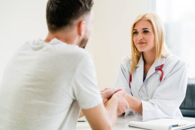 Kadın doktor hastane office odasında erkek hasta ile karşılıklı yapıyor. Sağlık ve Medikal hizmet meslekleri.