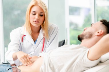 Kadın doktor konuşuyor ve erkek hasta hastane ofisinde inceleyerek. Sağlık ve tıbbi hizmet.