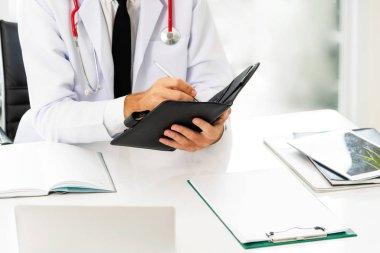 Doktor ofisinde hastanede bir kitap üzerine not yazarken okuma. Tıbbi ve sağlık kavramı.
