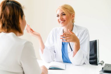 Kadın doktor konuşuyor ve Bayan hasta hastane ofisinde inceleyerek. Sağlık ve tıbbi hizmet.