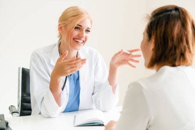 Kadın doktor konuşuyor ve Bayan hasta hastane ofisinde inceleyerek. Sağlık ve tıbbi hizmet.