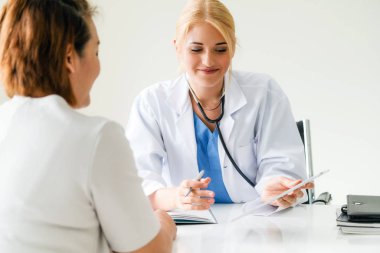 Kadın doktor konuşuyor ve Bayan hasta hastane ofisinde inceleyerek. Sağlık ve tıbbi hizmet.