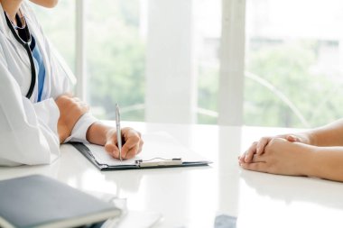 Kadın doktor görüşmeler yazarken bayan hasta için hastanın sağlık kaydının hastane ofiste. Sağlık ve tıbbi hizmet.