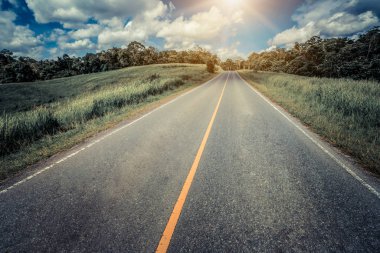 Tepe yaz günü mavi gökyüzünde üzerinde beyaz bulutlar altında yeşil çim sahası üzerinden karayolu yol. Yol yolculuk seyahat konsepti.