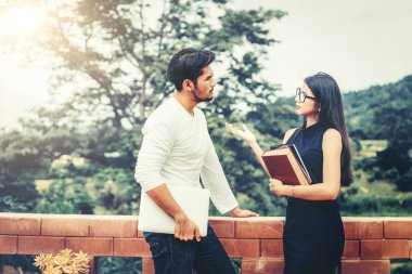 İki öğrenci kitap ve üniversitede konuşurken laptop ile. Eğitim kavramı kolej.