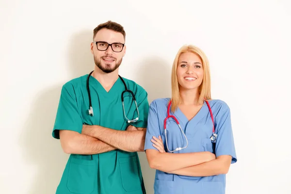 Portrait of confident GP doctor and surgical doctor with arms crossed on white background.