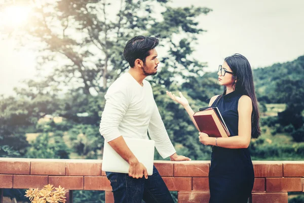 İki öğrenci kitap ve üniversitede konuşurken laptop ile. Eğitim kavramı kolej.