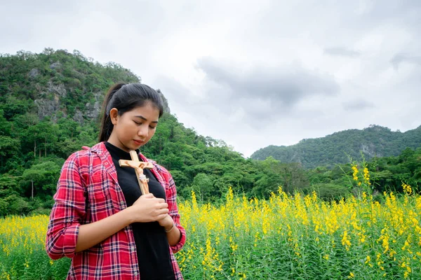 Young beautiful woman praying on nature background. Hope and faith concept.