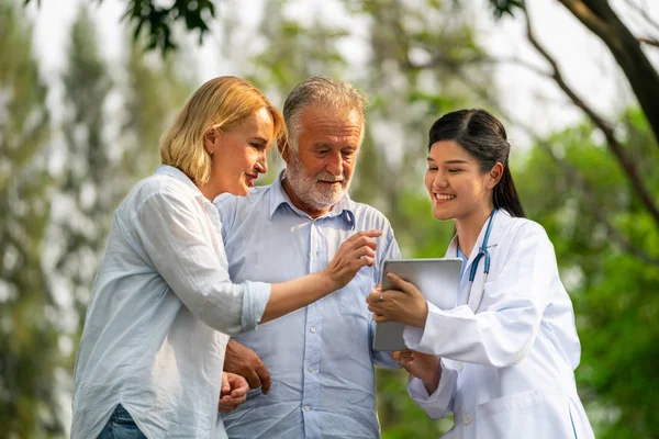 Üst düzey iki adam ve kadın genç hemşire veya parkta caregiver söz. Olgun insanlar sağlık ve tıbbi personel hizmet anlayışı.