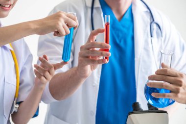 Laboratuvarda deney tüpü ve bilimsel aletlerdeki biyokimya örneklerini incelerken laboratuvar önlüğü giyen bir grup bilim adamı. Bilim teknolojisi araştırma ve geliştirme konsepti.