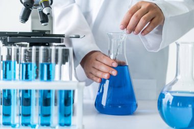 Laboratuvarda çalışan ve deney tüpündeki biyokimya örneklerini inceleyen kadın bilim adamı. Bilim teknolojisi araştırma ve geliştirme konsepti.