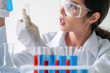 Laboratuvarda çalışan ve deney tüpündeki biyokimya örneklerini inceleyen kadın bilim adamı. Bilim teknolojisi araştırma ve geliştirme konsepti.