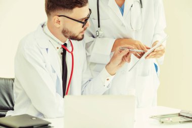 Doktor hastane ofis dizüstü bilgisayar masanın üzerinde başka bir doktor hasta sağlık hakkında tartışma ile çalışma.
