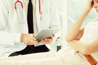 Erkek doktor konuşuyor ve Bayan hasta hastane ofisinde inceleyerek. Sağlık ve tıbbi hizmet.