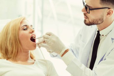 Genç yakışıklı dişçi diş diş kliniği, dişçi sandalyeye mutlu kadın hasta oturan incelenmesi. Diş Hekimliği bakım kavramı.