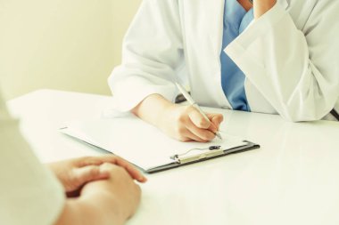 Kadın doktor görüşmeler yazarken bayan hasta için hastanın sağlık kaydının hastane ofiste. Sağlık ve tıbbi hizmet.