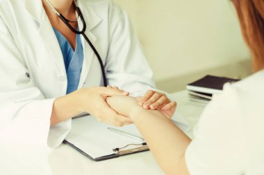 Kadın doktor hastane ofiste bayan hasta için eller tarafından hasta darbe incelenirken konuşuyor. Sağlık ve tıbbi hizmet.