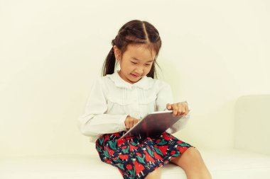 Tablet bilgisayar ile beyaz arka plan üzerinde küçük mutlu çocuk. Çocukluk yaşam tarzı.