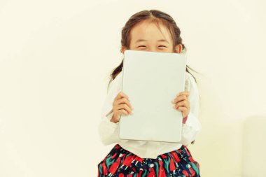 Tablet bilgisayar ile beyaz arka plan üzerinde küçük mutlu çocuk. Çocukluk yaşam tarzı.