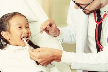 Mutlu çocuk diş diş kliniği içinde inceleyerek dostu genç diş hekimi. Diş Hekimliği kavramı.