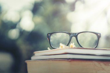 Yumuşak odak retro tarzı kitap ve göz gözlük doğa arka plan ile. Okuma ve eğitim kavramı.