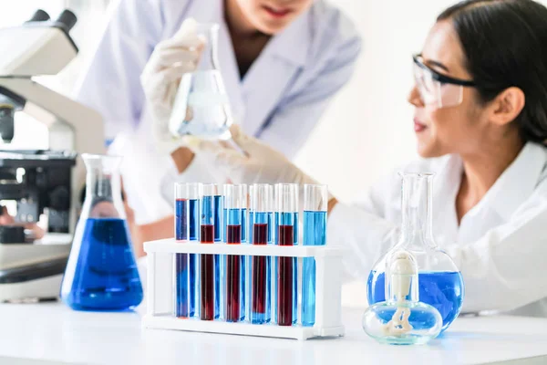 Group of scientists wearing lab coat working in laboratory while examining biochemistry sample in test tube and scientific instruments. Science technology research and development study concept.