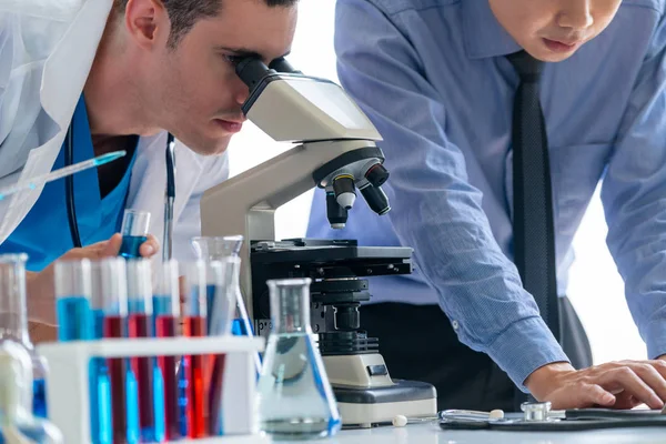 Group of scientists wearing lab coat working in laboratory while examining biochemistry sample in test tube and scientific instruments. Science technology research and development study concept.