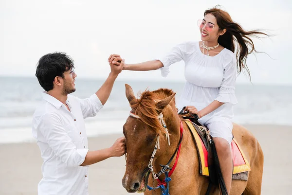 若いカップルがビーチで夏休みに新婚旅行乗馬 — ストック写真