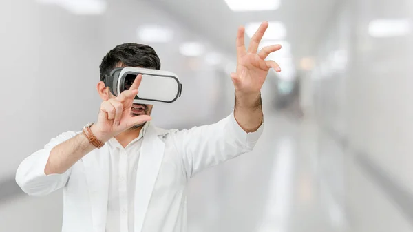 Male doctor wearing VR virtual reality goggles in the hospital. Medical technology research institute and doctor staff service concept.