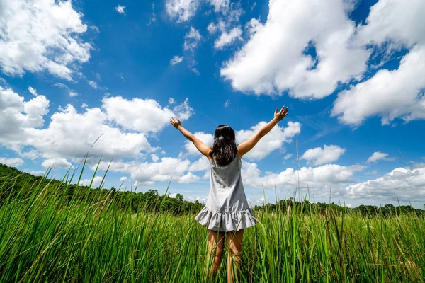 夏の日の晴れた青空に腕を広める緑の草の牧草地に若い美しい女性 逃走と瞑想の概念 — ストック写真