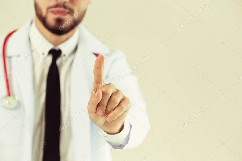 Male doctor pointing finger at blank space on white background. Selective focus at doctors finger.