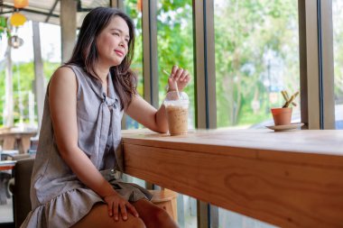 Yaz aylarında bir kafede oturan genç Asyalı güzel kadın.