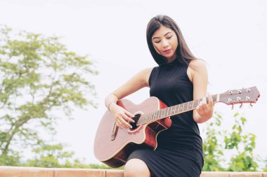 Mutlu kadın doğa arka plan ile gitar çalıyor. Müzik ve gevşeme kavramı.