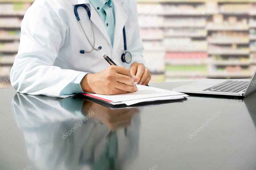 Pharmacist writes on documents at pharmacy.