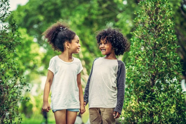 stock image Happy little boy and girl in the park. Two African American children together in the garden.