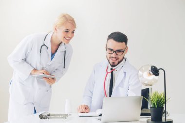 Doktor hastane ofis dizüstü bilgisayar masanın üzerinde başka bir doktor hasta sağlık hakkında tartışma ile çalışma.