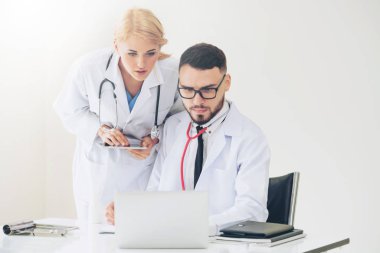 Doktor hastane ofis dizüstü bilgisayar masanın üzerinde başka bir doktor hasta sağlık hakkında tartışma ile çalışma.