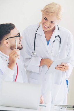 Doktor hastane ofis dizüstü bilgisayar masanın üzerinde başka bir doktor hasta sağlık hakkında tartışma ile çalışma.