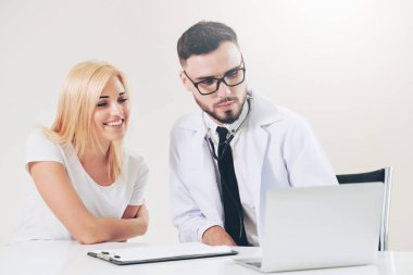 Erkek doktor hastane ofiste bayan hasta masada dizüstü bilgisayarda hastalar sağlık verilere bakarken konuştuğu. Sağlık ve tıbbi hizmet.