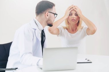 Erkek doktor hastane ofiste bayan hasta masada dizüstü bilgisayarda hastalar sağlık verilere bakarken konuştuğu. Sağlık ve tıbbi hizmet.
