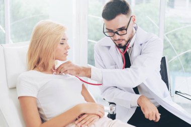 Erkek doktor konuşuyor ve Bayan hasta hastane ofisinde inceleyerek. Sağlık ve tıbbi hizmet.
